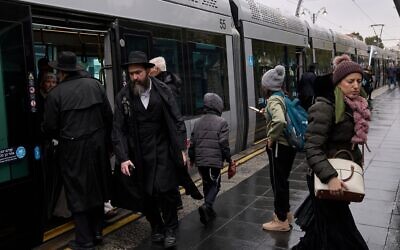 Des passagers descendant d'un tramway par un matin pluvieux, alors que la tempête Byron s'abat sur Jérusalem, le 10 décembre 2025. (Crédit : Leo Correa/AP Photo)