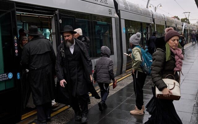 Des passagers descendant d'un tramway par un matin pluvieux, alors que la tempête Byron s'abat sur Jérusalem, le 10 décembre 2025. (Crédit : Leo Correa/AP Photo)