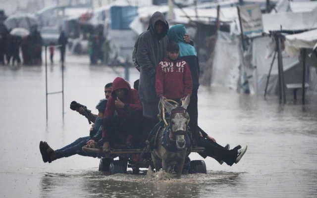 Des Palestiniens traversent une rue inondée après de fortes pluies à Khan Younès, dans le sud de la bande de Gaza, le 11 décembre 2025. (Crédit : AP Photo/Abdel Kareem Hana)