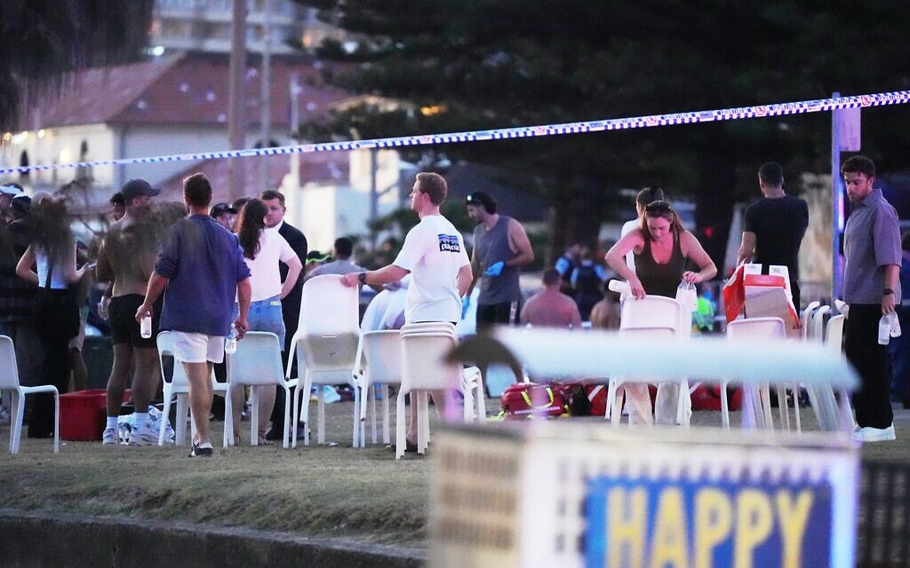 Des personnes et des secouristes réunis à l'endroit où une fête était organisée pour la première bougie de Hanoukka, puis où une fusillade a été signalée, à Bondi Beach, à Sydney, le 14 décembre 2025. (Crédit : Mark Baker/AP)
