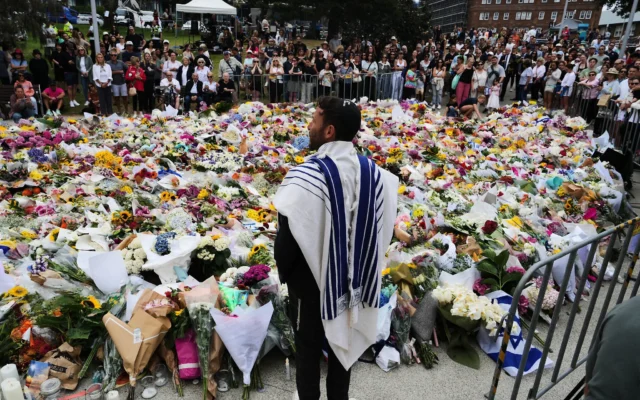 Le rabbin Yossi Friedman s'adresse à la foule rassemblée devant le mémorial fleuri du Bondi Pavilion à Bondi Beach après l'attaque terroriste antisémite perpétrée dimanche à Sydney, en Australie, le 16 décembre 2025,. (Crédit : AP Photo/Mark Baker) Le rabbin Yossi Friedman s'adresse à la foule rassemblée devant le mémorial fleuri du Bondi Pavilion à Bondi Beach après l'attaque terroriste antisémite perpétrée dimanche à Sydney, en Australie, le 16 décembre 2025,. (Crédit : AP Photo/Mark Baker)