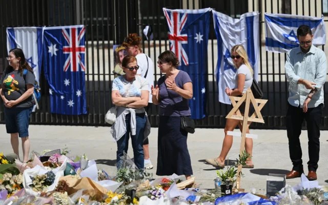 Des personnes rassemblées autour d'un hommage floral, devant le Bondi Pavilion, à Bondi Beach, à Sydney, le 18 décembre 2025. (Crédit : Steve Markham/AP) Des personnes rassemblées autour d'un hommage floral, devant le Bondi Pavilion, à Bondi Beach, à Sydney, le 18 décembre 2025. (Crédit : Steve Markham/AP)