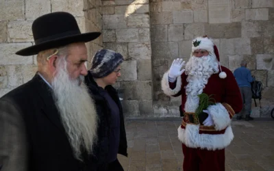 Illustration : Issa Kassissieh, 47 ans, qui accomplit sa 18ᵉ année déguisé en Père Noël, saluant la foule lors de sa tournée annuelle, dans la Vieille Ville de Jérusalem, le 18 décembre 2025. (Crédit : Leo Correa/AP)