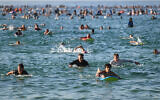 Des surfeurs et des nageurs se rendent à l'océan en hommage aux victimes de la fusillade survenue dimanche dernier à Bondi Beach, à Sydney, vendredi 19 décembre 2025. (Crédit : AP Photo/Steve Markham)