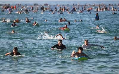 Des surfeurs et des nageurs se rendent à l'océan en hommage aux victimes de la fusillade survenue dimanche dernier à Bondi Beach, à Sydney, vendredi 19 décembre 2025. (Crédit : AP Photo/Steve Markham)