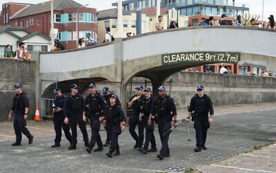 Des agents de sécurité ratissant une zone à Bondi Beach, à Sydney, avant une cérémonie marquant la Journée nationale de réflexion pour les victimes et les survivants de l'attaque terroriste meurtrière qui a visé un événement organisé par la communauté juive à Bondi Beach une semaine plus tôt, le 21 décembre 2025. (Crédit : Mark Baker/AP)