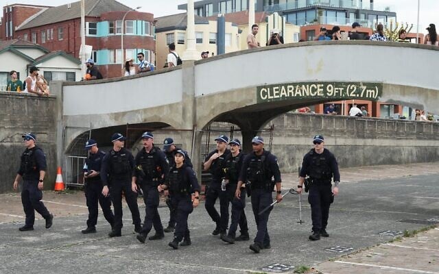 Des agents de sécurité ratissant une zone à Bondi Beach, à Sydney, avant une cérémonie marquant la Journée nationale de réflexion pour les victimes et les survivants de l'attaque terroriste meurtrière qui a visé un événement organisé par la communauté juive à Bondi Beach une semaine plus tôt, le 21 décembre 2025. (Crédit : Mark Baker/AP)