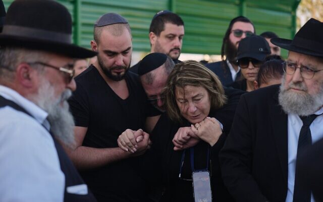 Annie (au centre) est réconfortée lors des funérailles de son fils Dan Elkayam, tué lors de l'attentat terroriste perpétré à Sydney pendant la fête de Hanoukka, dans un cimetière d'Ashdod, le 25 décembre 2025. (Crédit : Ariel Schalit/AP Photo)