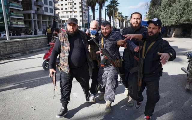 Un policier blessé par un jet de pierre est évacué de la zone après des affrontements entre manifestants alaouites et contre-manifestants à Lattaquié, région côtière de Syrie, le 28 décembre 2025. (Crédit : AP/Omar Albam)