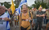 D'anciens pilotes de l'armée de l'air et des réservistes, accompagnés d'autres personnes, manifestent contre la poursuite de la guerre à Gaza et pour la libération des otages détenus dans la bande de Gaza, près de la base militaire de Kirya à Tel Aviv, le 12 août 2025. (Crédit : Avshalom Sassoni/Flash90)