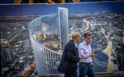 Des passants devant une affiche représentant une tour en spirale en construction à Tel Aviv, le 17 novembre 2025. Illustration (Crédit : Miriam Alster/FLASH90)