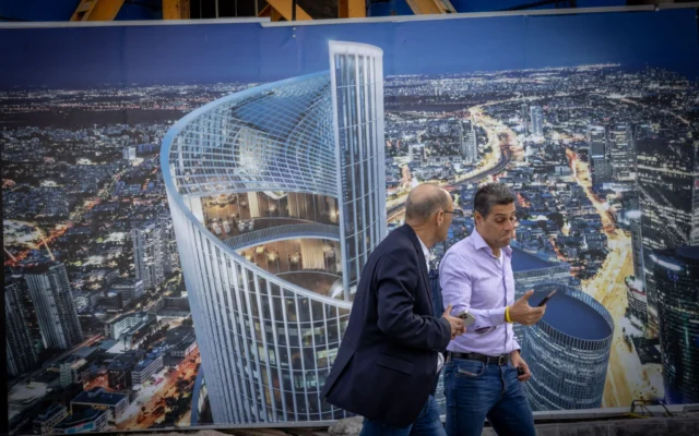 Des passants devant une affiche représentant une tour en spirale en construction à Tel Aviv, le 17 novembre 2025. Illustration (Crédit : Miriam Alster/FLASH90)