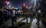 Des hommes ultra-orthodoxes bloquant la Route 4 lors d'une manifestation contre l'emprisonnement d'étudiants de yeshiva qui n'ont pas respecté un ordre de conscription de l'armée israélienne, à Bnei Brak, le 8 décembre 2025. (Crédit : David Cohen/Flash90)