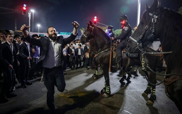 Des hommes ultra-orthodoxes bloquant la Route 4 lors d'une manifestation contre l'emprisonnement d'étudiants de yeshiva qui n'ont pas respecté un ordre de conscription de l'armée israélienne, à Bnei Brak, le 8 décembre 2025. (Crédit : David Cohen/Flash90)