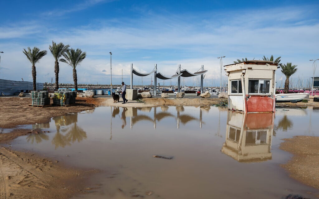 Des personnes aperçues près de la plage dans la ville d'Ashdod, au sud d'Israël, après de fortes pluies et des vents violents, le 10 décembre 2025. (Crédit : Flash90)