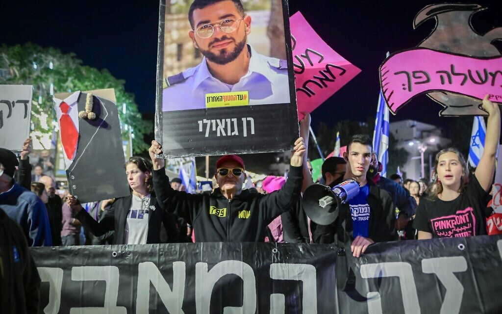 Un homme brandissant une photo de Ran Gvili, le dernier otage dont le corps est toujours détenu par des groupes terroristes à Gaza, qui prétendent ne pas savoir où il se trouve, lors d'une manifestation contre le Premier ministre Benjamin Netanyahu et son gouvernement, sur la Place Habima, à Tel Aviv, le 13 décembre 2025. (Crédit : Avshalom Sassoni/Flash90)