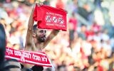 Un supporter du Hapoel Tel Aviv brandit un t-shirt controversé sur lequel on peut lire "Against the scum" (Contre la racaille), avec les logos de la police israélienne, du parti interdit Kach et du Maccabi Tel Aviv, au stade Bloomfield de Tel Aviv, le 20 décembre 2025. (Crédit : Danny Maron/Flash90)