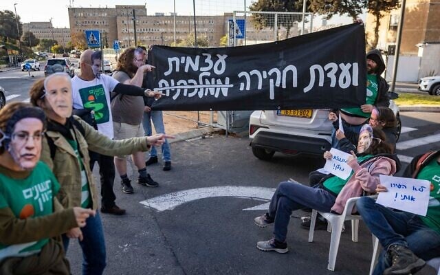 Des militants réclamant la création d'une commission d'enquête nationale sur le pogrom perpétré par le groupe terroriste palestinien du Hamas le 7 octobre 2023, devant le bureau du Premier ministre, à Jérusalem, le 22 décembre 2025. (Crédit : Chaïm Goldberg/Flash90)
