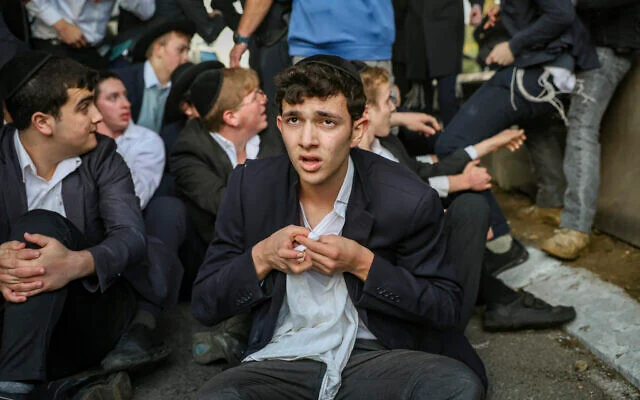 Des hommes ultra-orthodoxes lors d’une manifestation bloquant la route 4 en opposition à l’emprisonnement des étudiants de yeshiva qui refusent de répondre à l'ordre de conscription de l’armée, près de Bnei Brak, le 28 décembre 2025. (David Cohen/Flash90)