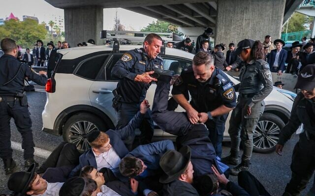 Des ultra-orthodoxes affrontant la police lors d'une manifestation bloquant la Route 4 pour protester contre l'emprisonnement d'étudiants de yeshiva qui ont refusé de se conformer à un ordre de conscription militaire, près de Bnei Brak, le 28 décembre 2025. (Crédit : David Cohen/Flash90)