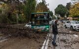 Un bus est immobilisé alors qu'un arbre s'effondre sur une route en raison des vents violents et des pluies torrentielles qui s'abattent sur Jérusalem, le 29 décembre 2025. (Crédit : Yonatan Sindel/Flash90)