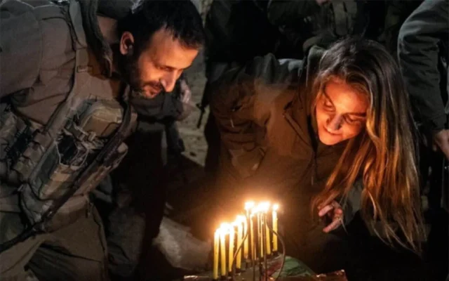 La sergente (rés.) Dana Silberman Sitton, sœur de Shiri Bibas, otage assassinée, allume une bougie sur la hannoukia de ses parents assassinés, à Gaza, le 21 décembre 2025. (Crédit : Tsahal)