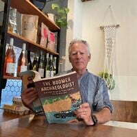 L'archéologue Thomas Levy avec son nouveau livre de mémoires « The Boomer Archaeologist », à Jérusalem, en septembre 2025. (Crédit : Rossella Tercatin/Times of Israel)