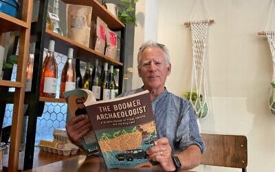 L'archéologue Thomas Levy avec son nouveau livre de mémoires « The Boomer Archaeologist », à Jérusalem, en septembre 2025. (Crédit : Rossella Tercatin/Times of Israel)