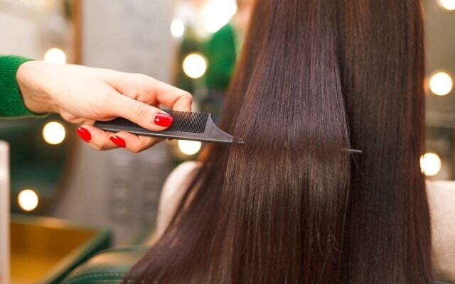Illustration : Une coiffeuse peignant des cheveux après un traitement de lissage longue durée. (Crédit : Andrii Borodai via iStock by Getty Images)
