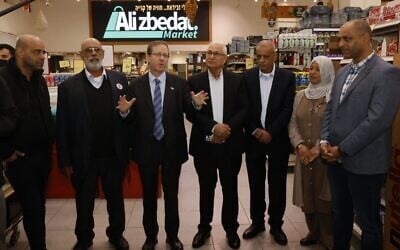 Le président Isaac Herzog (3ᵉ à partir de la gauche) en visite dans l'épicerie d'Ali Zbedat, qui a contribué à déclencher une grève générale dans la société arabe contre la criminalité violente, lors d'un déplacement à Sakhnin en compagnie du maire de cette ville du nord, Mazen Ghnaim (à sa gauche), le 29 janvier 2026. (Crédit : Autorisation)