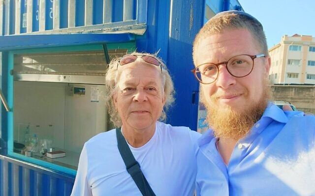Le rabbin Noach Koncepolski se tient aux côtés d'une passante devant le kiosque qu'il a fondé à Bondi Beach, en Australie, en mémoire des victimes de l'attentat terroriste perpétré lors de Hanoukka, en décembre 2025.(Autorisation)