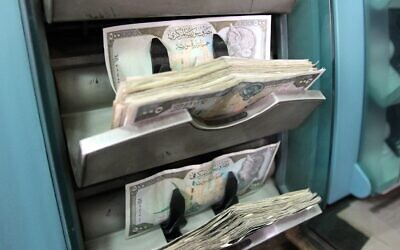 Illustration : billets syriens comptés par une machine dans une banque à Damas, le 28 février 2012. (Crédit : Anwar AMRO / AFP)