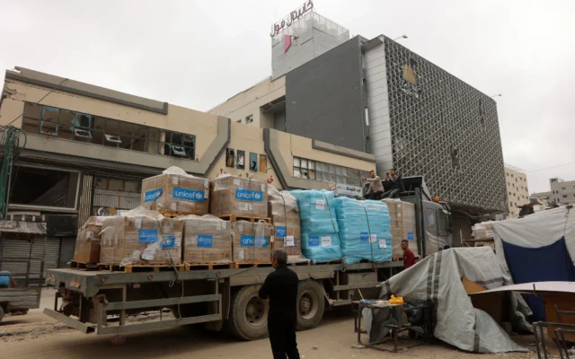 Un Palestinien se tient à côté d'un camion transportant des fournitures humanitaires de l'UNICEF devant un centre commercial de la ville de Gaza, le 12 mai 2025. (Crédit : Omar AL-QATTAA / AFP)