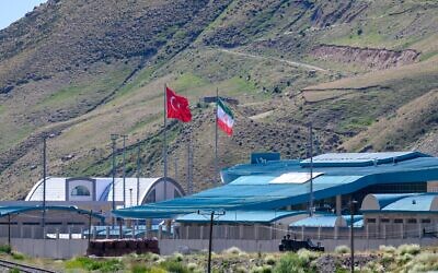 Les drapeaux iranien et turc flottent en Turquie au poste frontière de Razi-Kapikoy, dans le nord-est de la Turquie, le 19 juin 2025. (Crédit : Yasin AKGUL / AFP)