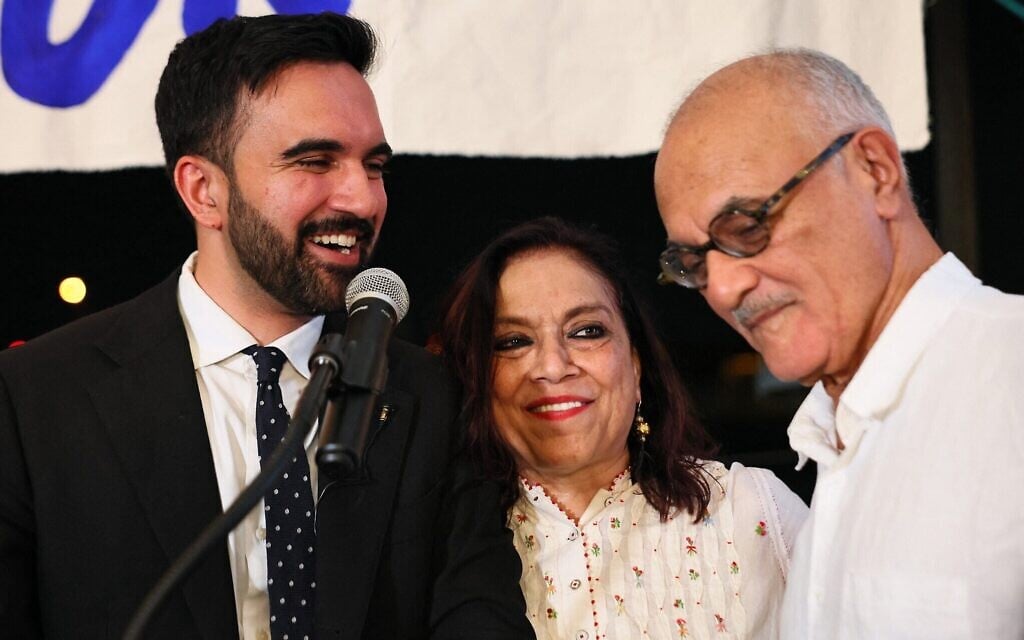 Zohran Mamdani aux côtés de sa mère Mira Nair et de son père Mahmood Mamdani lors d'une soirée électorale organisée dans le quartier de Long Island City, dans le Queens, à New York, le 24 juin 2025. (Crédit : Michael M. Santiago/Getty Images/AFP)