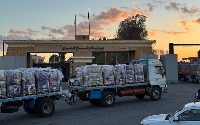 Des camions chargés d'aide humanitaire attendant, du côté égyptien du poste-frontière de Rafah, de pouvoir entrer dans la bande de Gaza, tôt le matin du 15 octobre 2025. (Crédit : AFP)