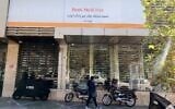Une Iranienne passe devant une succursale de la banque publique Melli, qui a absorbé les actifs de la défunte banque Ayandeh. Une pancarte en farsi sur la façade indique "Cette ancienne succursale de la banque Ayandeh fait désormais partie de la banque Melli", dans la capitale Téhéran, le 25 octobre 2025. (Crédit : ATTA KENARE / AFP)