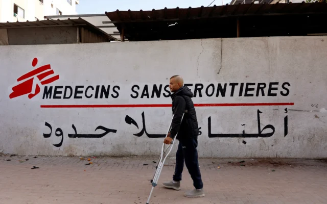 Un Palestinien marche avec ses béquilles, le soir du réveillon du Nouvel An, vers la clinique de Médecins Sans Frontières (MSF) dans le quartier d'al-Rimal de Gaza-City, le 31 décembre 2025. (Crédit : Omar AL-QATTAA / AFP)