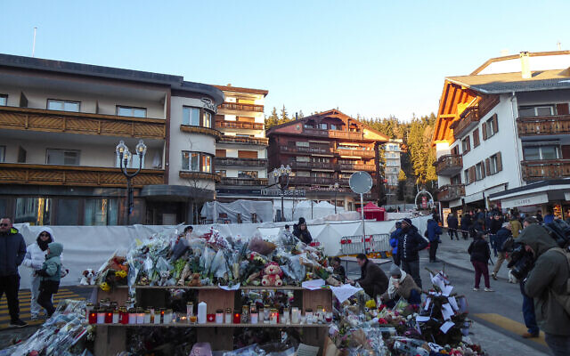 Des fleurs près du lieu où un incendie a ravagé un bar bondé pendant les célébrations du Nouvel An dans la station de ski alpine de Crans-Montana, en Suisse, le 1ᵉʳ janvier 2026. (Crédit :  Robin MILLARD / AFP)