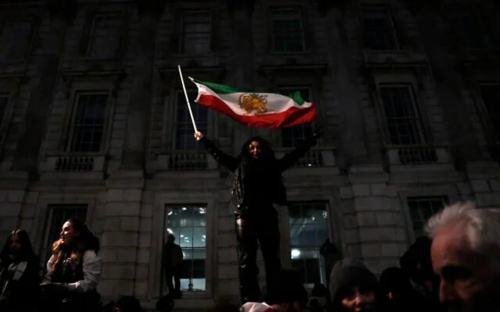 Un manifestant brandissant un drapeau iranien de l'époque du shah lors d'une manifestation contre la répression des manifestations en Iran par le régime iranien, dans le centre-ville de Londres, le 11 janvier 2026. (Crédit : Carlos Jasso/AFP)