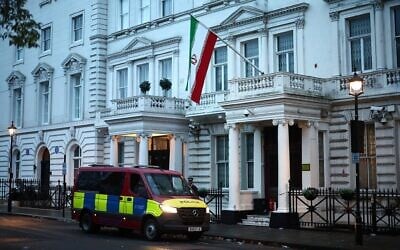Une fourgonnette de police en faction devant l'ambassade d'Iran, arborant le drapeau de la République islamique d'Iran, dans le centre de Londres, le 12 janvier 2026. (Crédit : HENRY NICHOLLS / AFP)