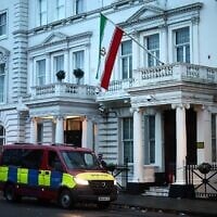 Un fourgon de police attendant devant l'ambassade d'Iran, arborant le drapeau de la République islamique d'Iran, dans le centre-ville de Londres, le 12 janvier 2026. (Crédit : Henry Nicholls/AFP)