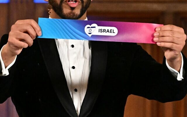 Le modérateur, le chanteur autrichien Cesar Sampson, tirant au sort le numéro d'Israël lors de la cérémonie de tirage au sort du Concours Eurovision de la chanson 2026, sur la scène de l'hôtel de ville de Vienne, en Autriche, le 12 janvier 2026. (Crédit : Joe Klamar/AFP)