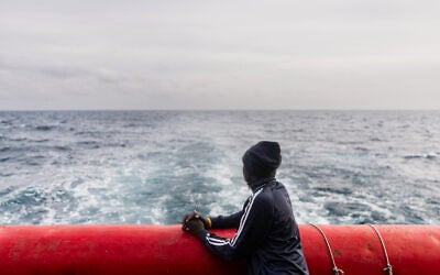 Un migrant soudanais contemple la mer depuis le pont arrière du navire de sauvetage « Ocean Viking », affrété par l’ONG SOS Méditerranée, qui navigue en mer Méditerranée en direction du port de débarquement désigné à Palerme, dans le sud de l’Italie, le 18 janvier 2026. (Photo : Sameer Al-DOUMY / AFP)