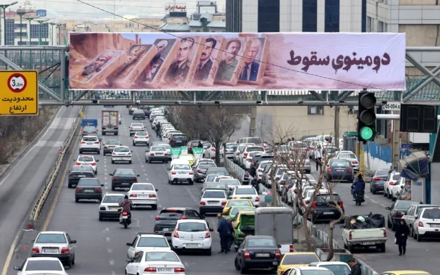 Des voitures roulent roule sous une banderole représentant des dirigeants passés et présents alors que la vie quotidienne reprend dans les rues après les manifestations nationales, dans la capitale iranienne Téhéran, le 19 janvier 2026. (Crédit: Atta Kenare/AFP)