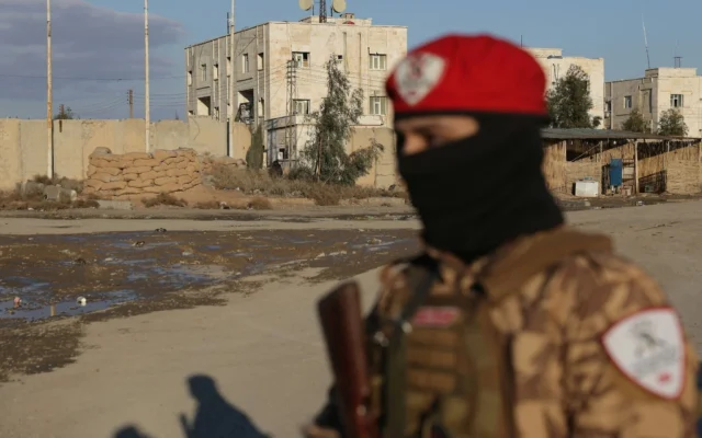 Un soldat du gouvernement syrien se tenant devant la prison d'al-Aktan, contrôlée par les Force démocratiques syriennes (FDS) et où sont détenus des membres du groupe terroriste sunnite État islamique (EI), alors que l'armée syrienne prend possession de la base militaire des FDS située à proximité, dans la ville de Raqqa, le 19 janvier 2026. (Crédit : Bakr Alkasem/AFP)