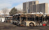 Cette photographie, prise lors d'un voyage organisé pour les médias étrangers, montre un représentant de la presse passant devant des bus incendiés dans un dépôt lors des récentes manifestations à Téhéran, le 21 janvier 2026. (Crédit : ATTA KENARE / AFP)