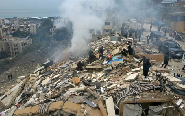 Des personnes recherchant leurs effets personnels parmi les décombres d'un bâtiment effondré, au lendemain d'une frappe aérienne israélienne dans le village de Qannarit, dans le sud du Liban, le 22 janvier 2026. (Crédit : Mahmoud Zayyat/AFP)