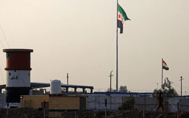 Les drapeaux nationaux de la Syrie (à gauche) et de l'Irak sont photographiés près de la frontière irako-syrienne, à Al-Qaim, à l'ouest de l'Irak, le 23 janvier 2026. (Crédit : AHMAD AL-RUBAYE / AFP)