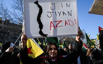 Une manifestante tenant une pancarte sur laquelle on peut lire « Femmes, vie, liberté », slogan politique kurde populaire devenu le cri de ralliement des manifestations qui ont eu lieu en Iran en réponse à la mort de Mahsa Amini, et décorée d'une tresse, symbole de résistance, lors d'une manifestation de solidarité avec les Kurdes du nord de la Syrie, place de la République, dans le centre de Paris, le 24 janvier 2026. Selon les Nations unies, plus de 134 000 personnes ont été déplacées dans le nord-est de la Syrie, après des affrontements et un accord de cessez-le-feu fragile entre les troupes gouvernementales et les Forces démocratiques syriennes (FDS) dirigées par les Kurdes. (Crédit : Blanca Cruz/AFP) Une manifestante tenant une pancarte sur laquelle on peut lire « Femmes, vie, liberté », slogan politique kurde populaire devenu le cri de ralliement des manifestations qui ont eu lieu en Iran en réponse à la mort de Mahsa Amini, et décorée d'une tresse, symbole de résistance, lors d'une manifestation de solidarité avec les Kurdes du nord de la Syrie, place de la République, dans le centre de Paris, le 24 janvier 2026. Selon les Nations unies, plus de 134 000 personnes ont été déplacées dans le nord-est de la Syrie, après des affrontements et un accord de cessez-le-feu fragile entre les troupes gouvernementales et les Forces démocratiques syriennes (FDS) dirigées par les Kurdes. (Crédit : Blanca Cruz/AFP)